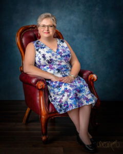 mylifesuchasitis.com elizabeth white 2020 offiical portrait sitting in leather chair. wearing a floral print sundress