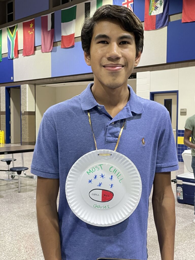 charlie wearing his swim team "medal" which is a paper plate with "Most Chill" written on it along with a drawing of a chill pill